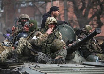 Anggota layanan pasukan Pro Rusia terlihat di atas kendaraan lapis baja selama konflik Ukraina-Rusia. Sumber foto : Reuters.