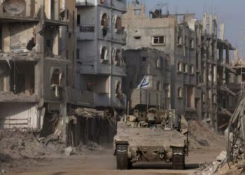 Sebuah kendaraan lapis baja melaju sementara bangunan-bangunan yang rusak terlihat di latar belakang, di tengah operasi darat yang sedang berlangsung oleh tentara Israel melawan kelompok Islamis Palestina, Hamas, di Jalur Gaza, 13 September 2024. REUTERS/Amir Cohen