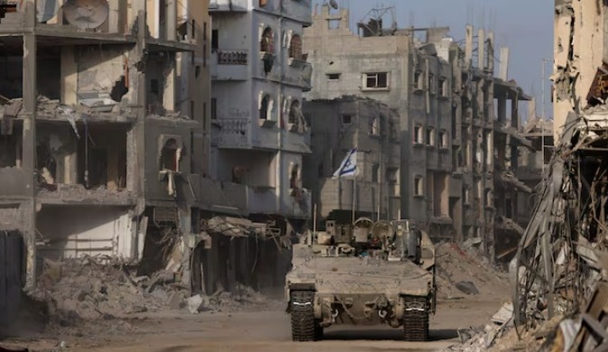 Sebuah kendaraan lapis baja melaju sementara bangunan-bangunan yang rusak terlihat di latar belakang, di tengah operasi darat yang sedang berlangsung oleh tentara Israel melawan kelompok Islamis Palestina, Hamas, di Jalur Gaza, 13 September 2024. REUTERS/Amir Cohen