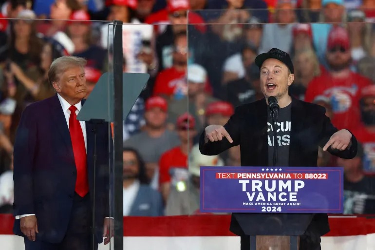 CEO Tesla dan pemilik X, Elon Musk, berbicara sementara calon presiden dari Partai Republik dan mantan Presiden AS, Donald Trump, memperhatikannya selama rapat umum di Butler, Pennsylvania pada 5 Oktober 2024 (Carlos Barria/Reuters).