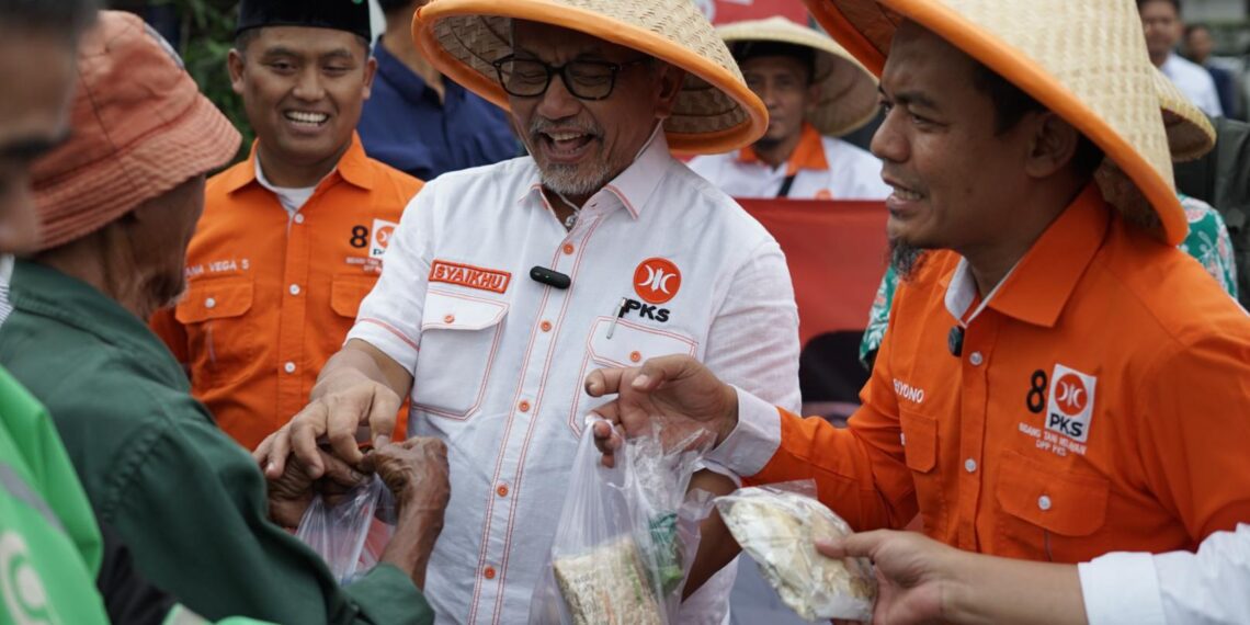 Ketua DPP PKS Bidang Tani dan Nelayan, Riyono Caping dan Presiden PKS Ahmad Syaikhu dalam aksi berbagi 1.000 paket sayuran dan 300 paket ikan asin kepada masyarakat di sekitar kantor DPTP PKS, Jakarta Selatan, Rabu (19/3/2025).