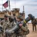 Seorang tentara Amerika membawa peluncur Javelin saat latihan militer antara Pasukan Demokratik Suriah (Syrian Democratic Forces) dan koalisi internasional pimpinan AS melawan kelompok Daesh, di wilayah pedesaan Deir Ezzor, timur laut Suriah, pada 7 Desember 2021. Sumber foto : AFP.
